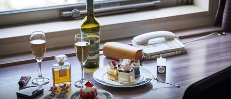 A table with a bottle of wine, glasses of champagne, a phone, a notepad, and a small dessert plate.
