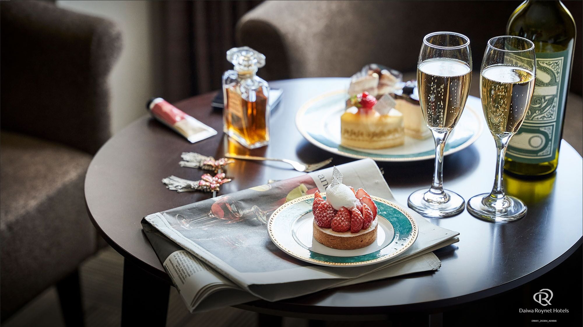A table with a dessert, two glasses of champagne, a bottle of wine, and a decorative bottle.