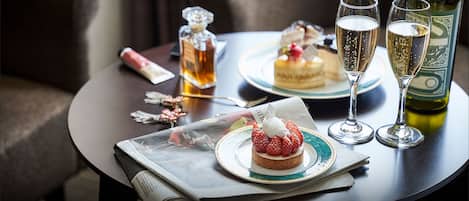 A table with a dessert, two glasses of champagne, a bottle of wine, and a decorative bottle.