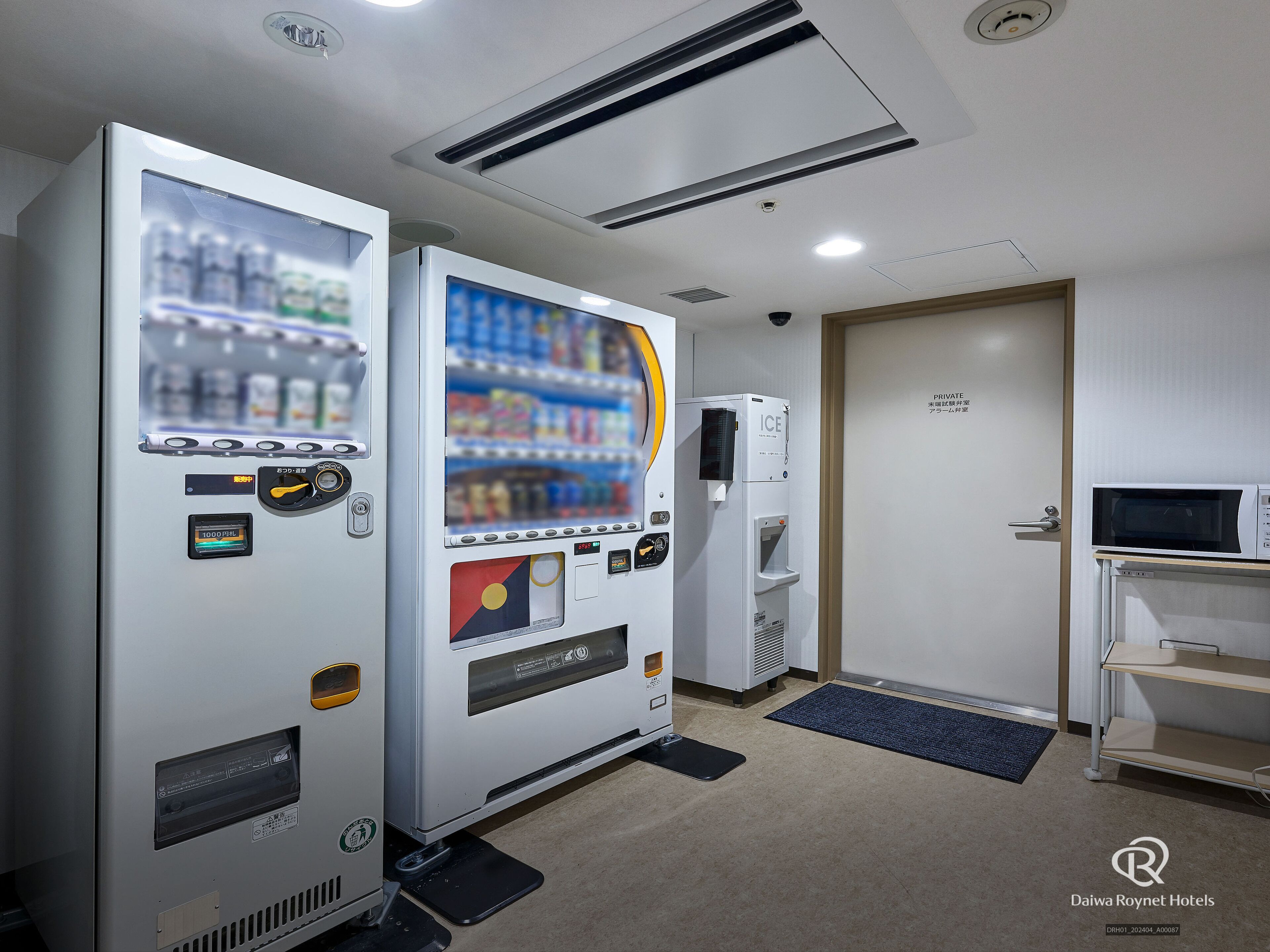 Een hotelkamer met een minibar, een magnetron en een deur naar een privébadkamer.