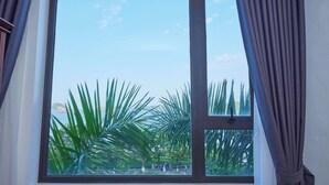 A window with a view of palm trees and a clear sky. - Gieng Ngoc Hotel (Hai Phong)