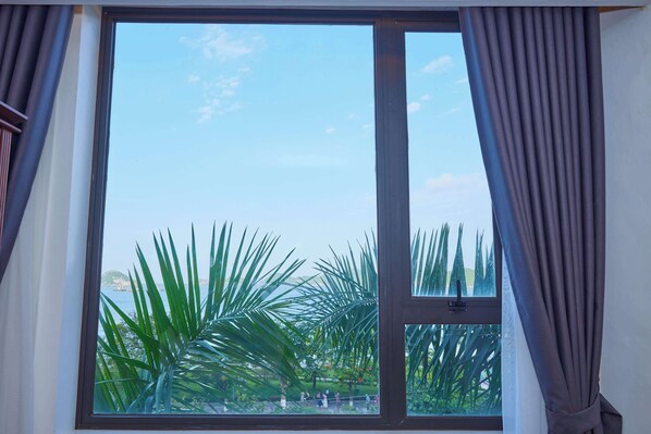 A window with a view of palm trees and a clear sky.