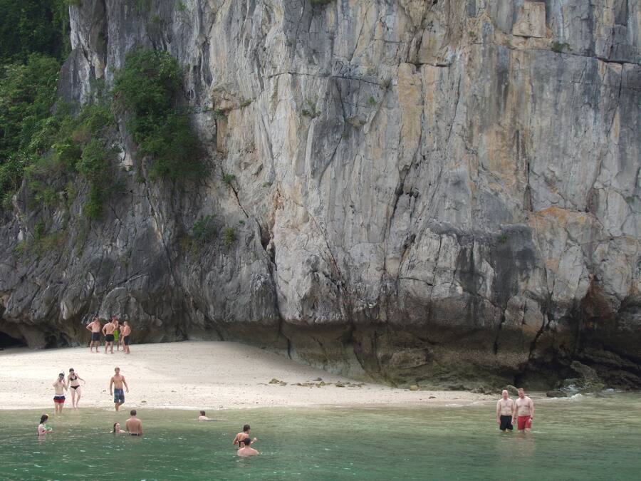 Una playa con agua cristalina y un acantilado rocoso.