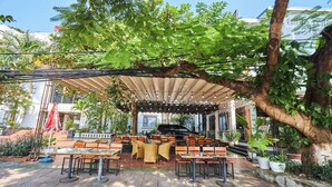 An outdoor cafe with tables and chairs, a covered seating area, and a piano. - Gieng Ngoc Hotel (Hai Phong)