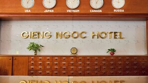 A hotel reception desk with a marble wall displaying room numbers and a sign reading "GIENG NGOC HOTEL". - Gieng Ngoc Hotel (Hai Phong)