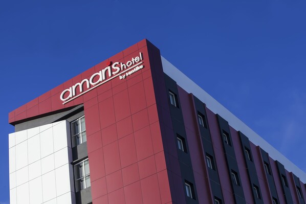 A modern hotel building with a prominent red and white facade, featuring the name 'amariShotel by senika' on the upper part. - Amaris Gorontalo (Gorontalo)