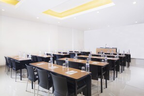 A conference room with multiple tables, chairs, water bottles, and a podium. - Amaris Gorontalo (Gorontalo)