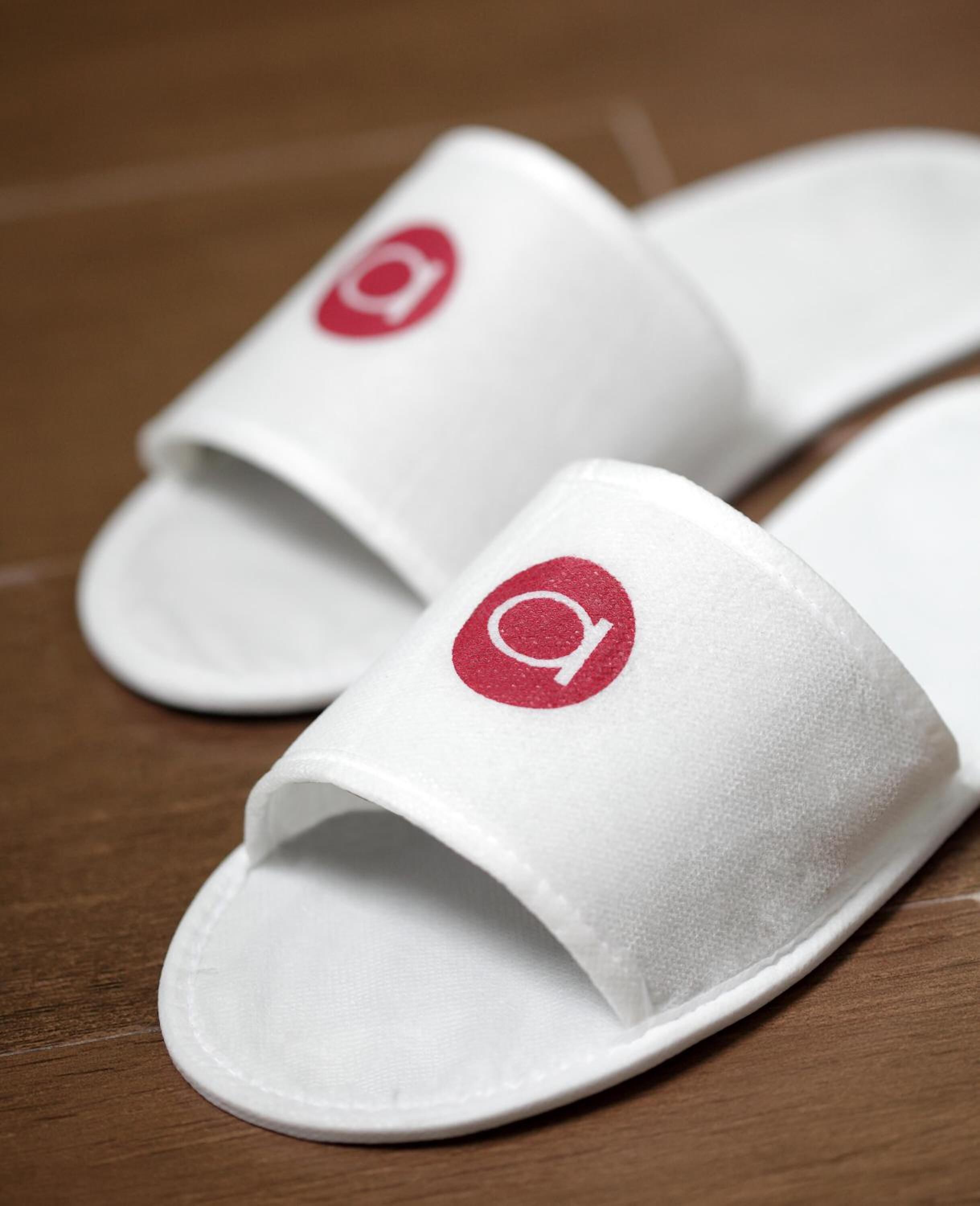 A pair of white slides with a red logo on the footrest.