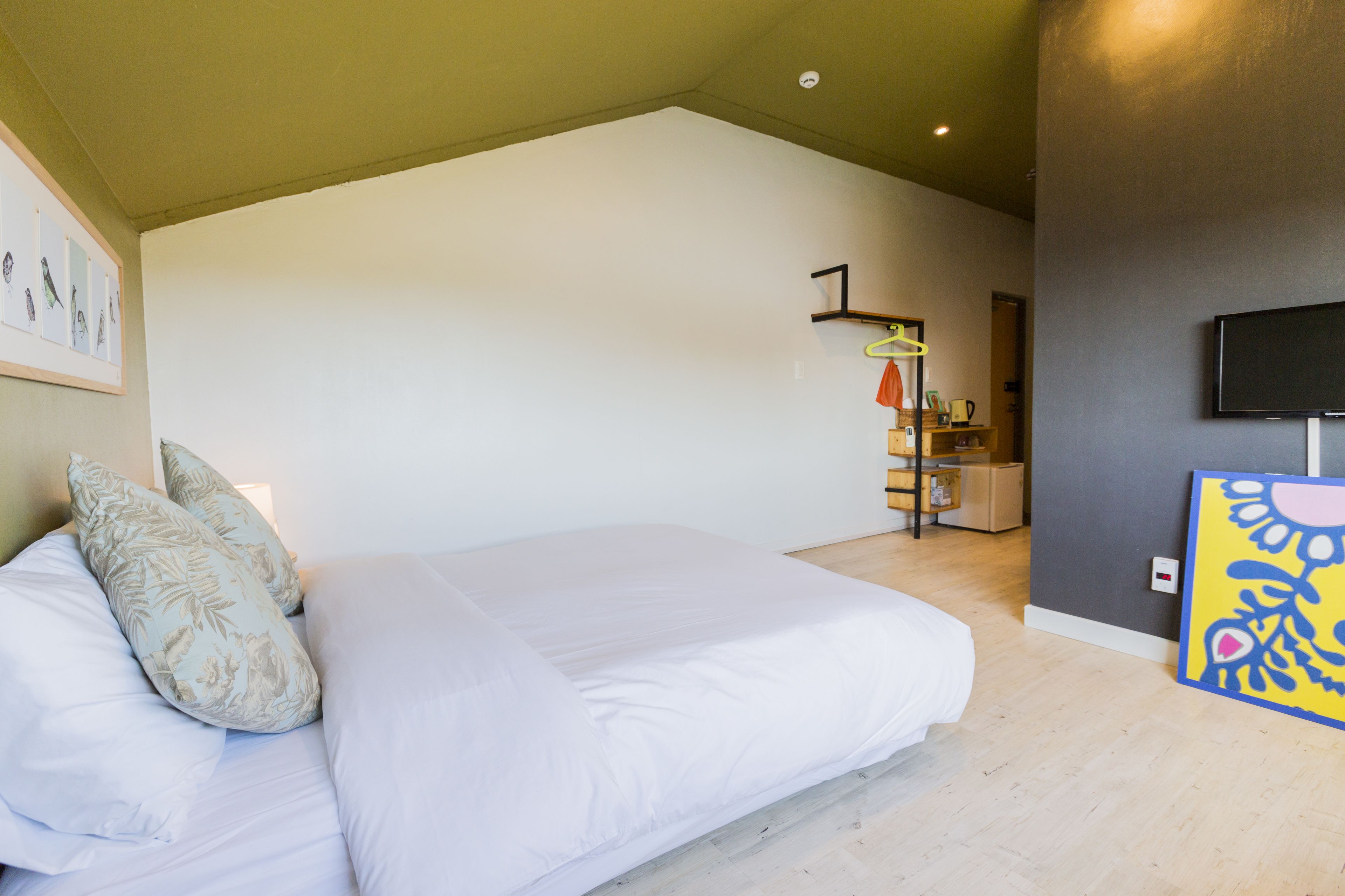 Quarto com cama, almofadas, televisão de tela plana e um quadro na parede.