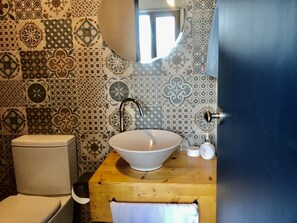 A bathroom with a white sink, a mirror, and a toilet. The walls are decorated with patterned tiles. - Maison de Ojolac (Seogwipo)