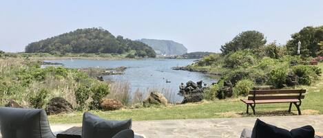 An outdoor seating area with a view of a lake and a distant island.