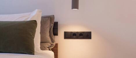Ein modernes Schlafzimmer mit Bett, Nachttisch und einer Wandsteckdose.