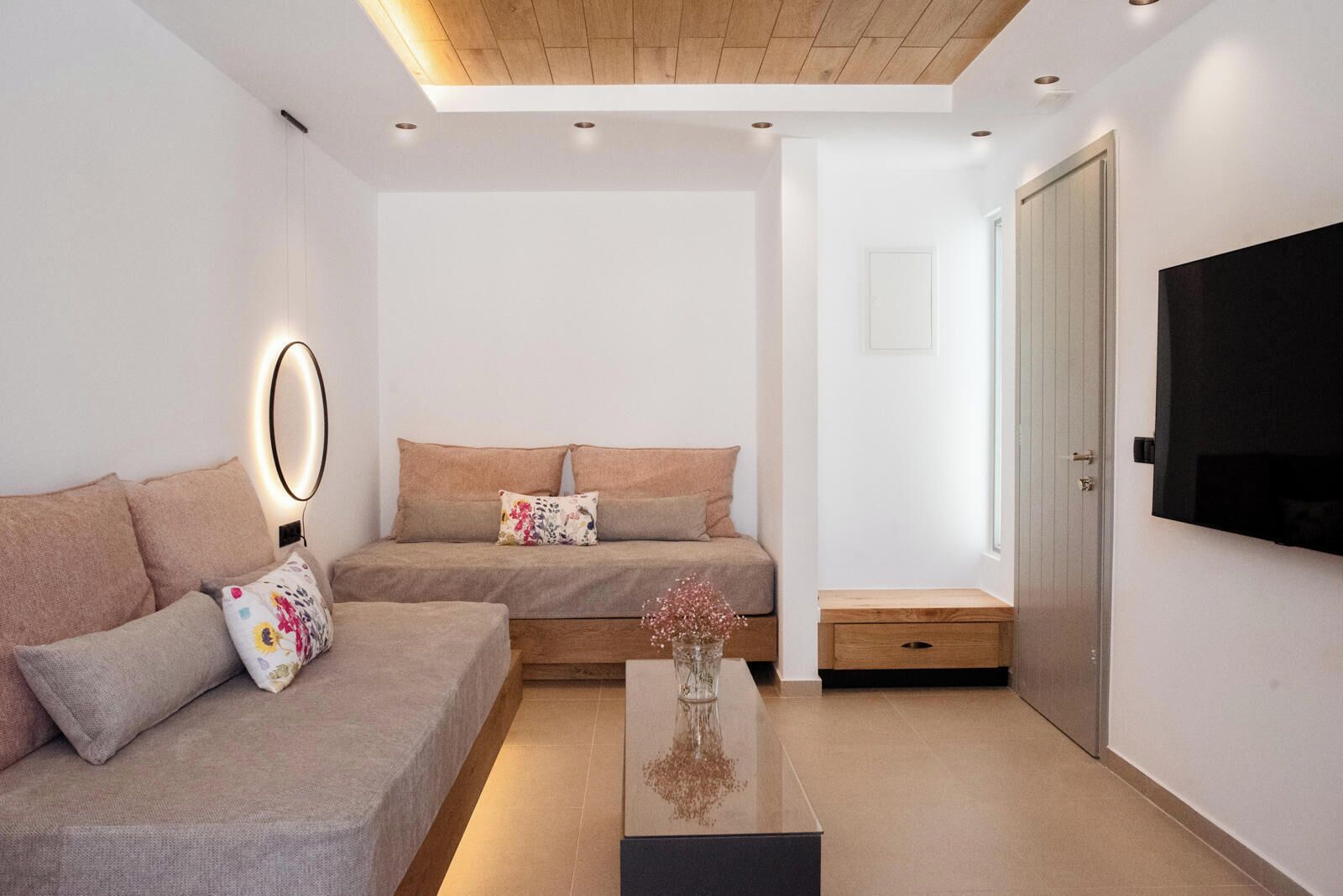 Una sala de estar moderna con un sofá, una mesa de centro y un televisor montado en la pared.