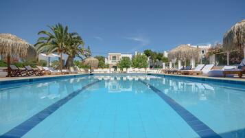 Una piscina con sillones de descanso y palmeras.