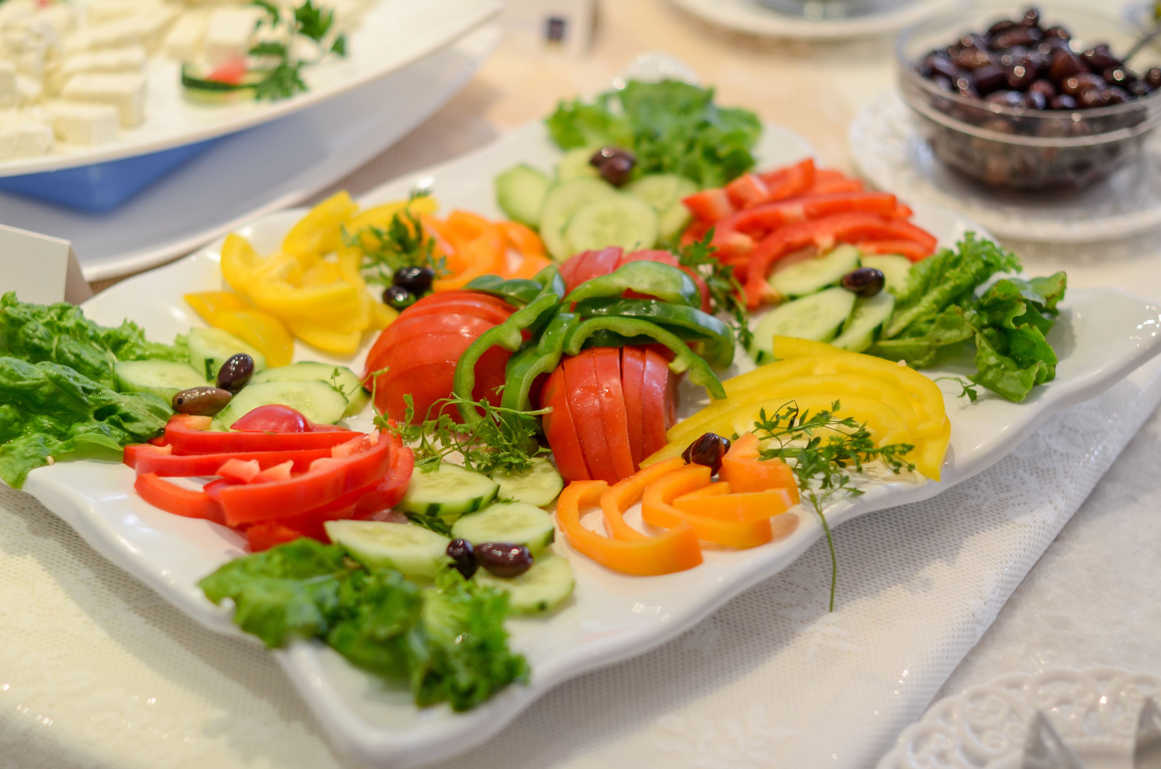 Une assiette rectangulaire blanche, garnie d’un assortiment de légumes et d’herbes aromatiques coupés en tranches.