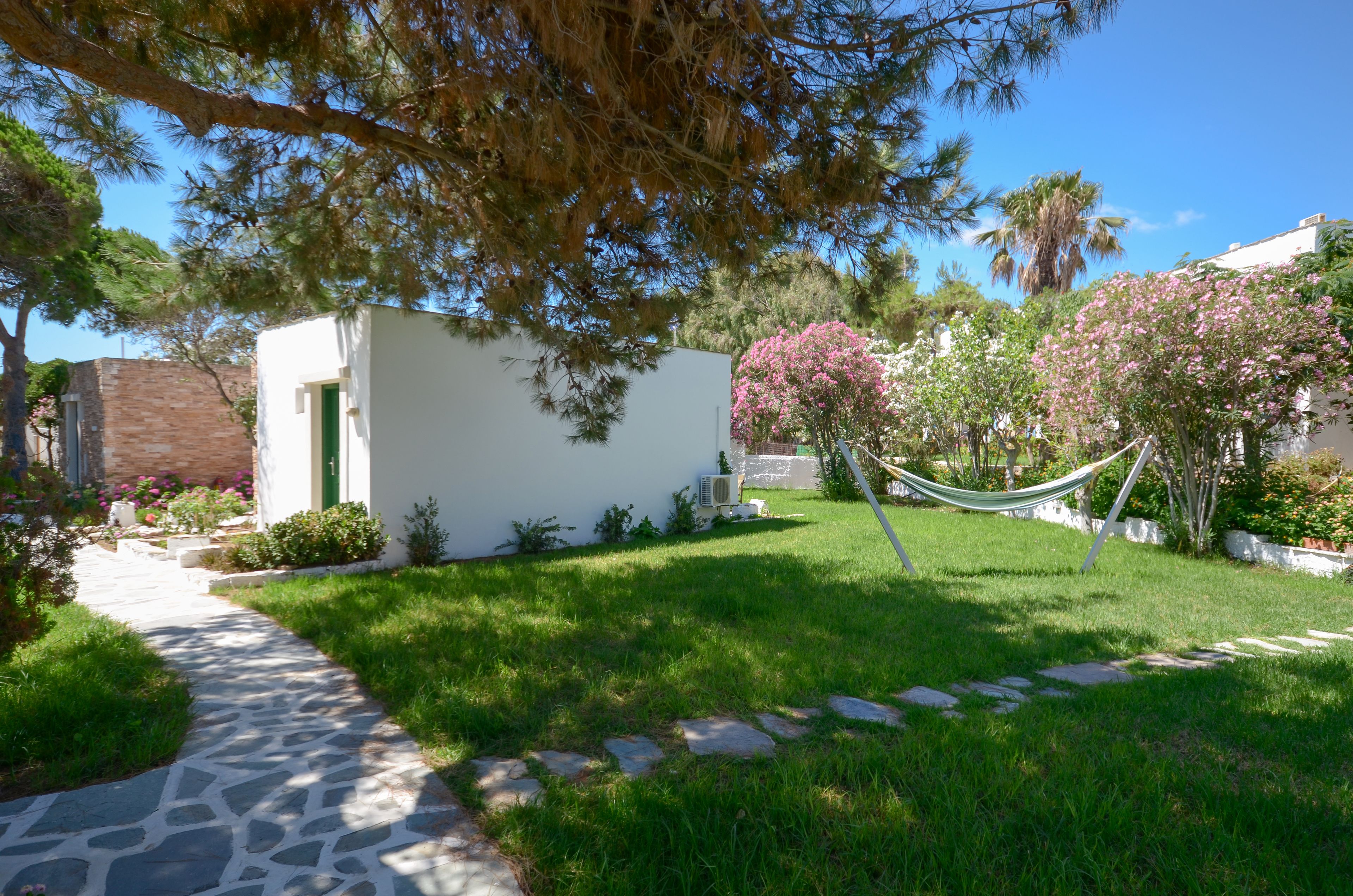 A garden with a stone pathway leading to a white building with a green door.
