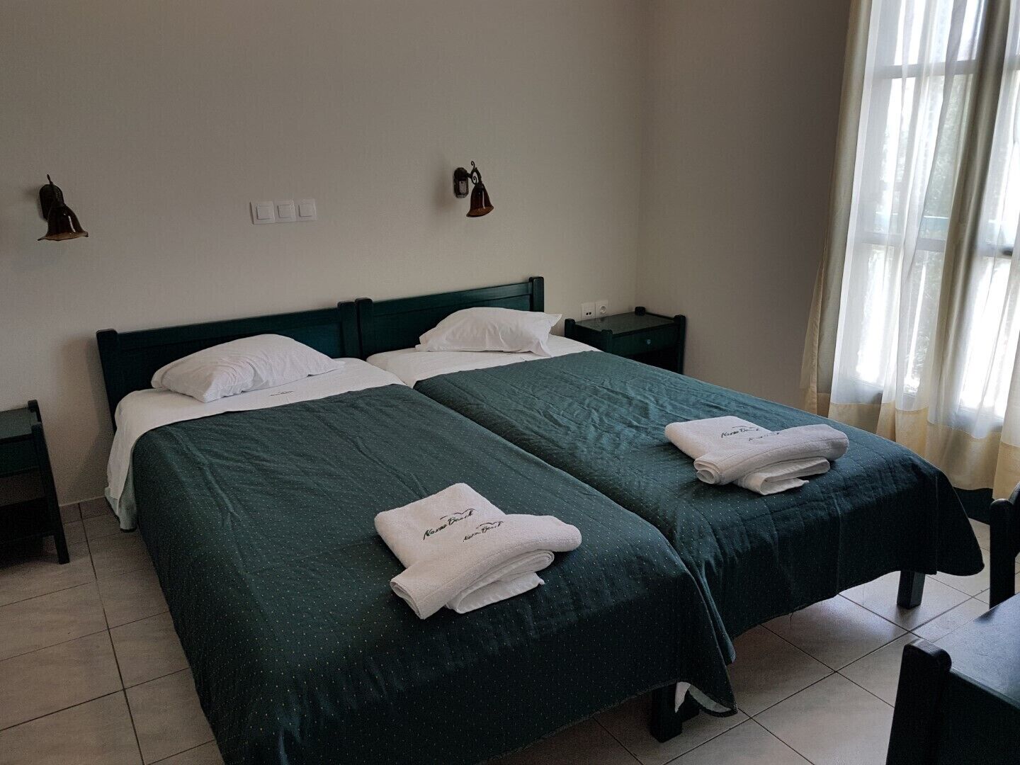 Una habitación de hotel con dos camas individuales, una mesita pequeña y una silla.
