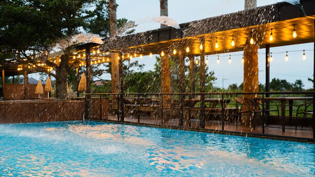 Un espace piscine extérieur agrémenté d’une pergola et de guirlandes lumineuses.