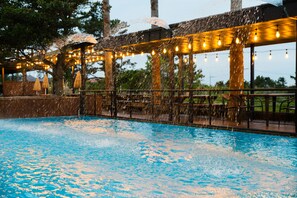 Un espace piscine extérieur agrémenté d’une pergola et de guirlandes lumineuses.