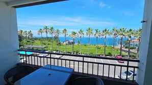 Un balcon avec vue sur l’océan et les palmiers.