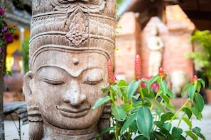 A carved stone pillar with intricate designs and a Buddha statue in the background.