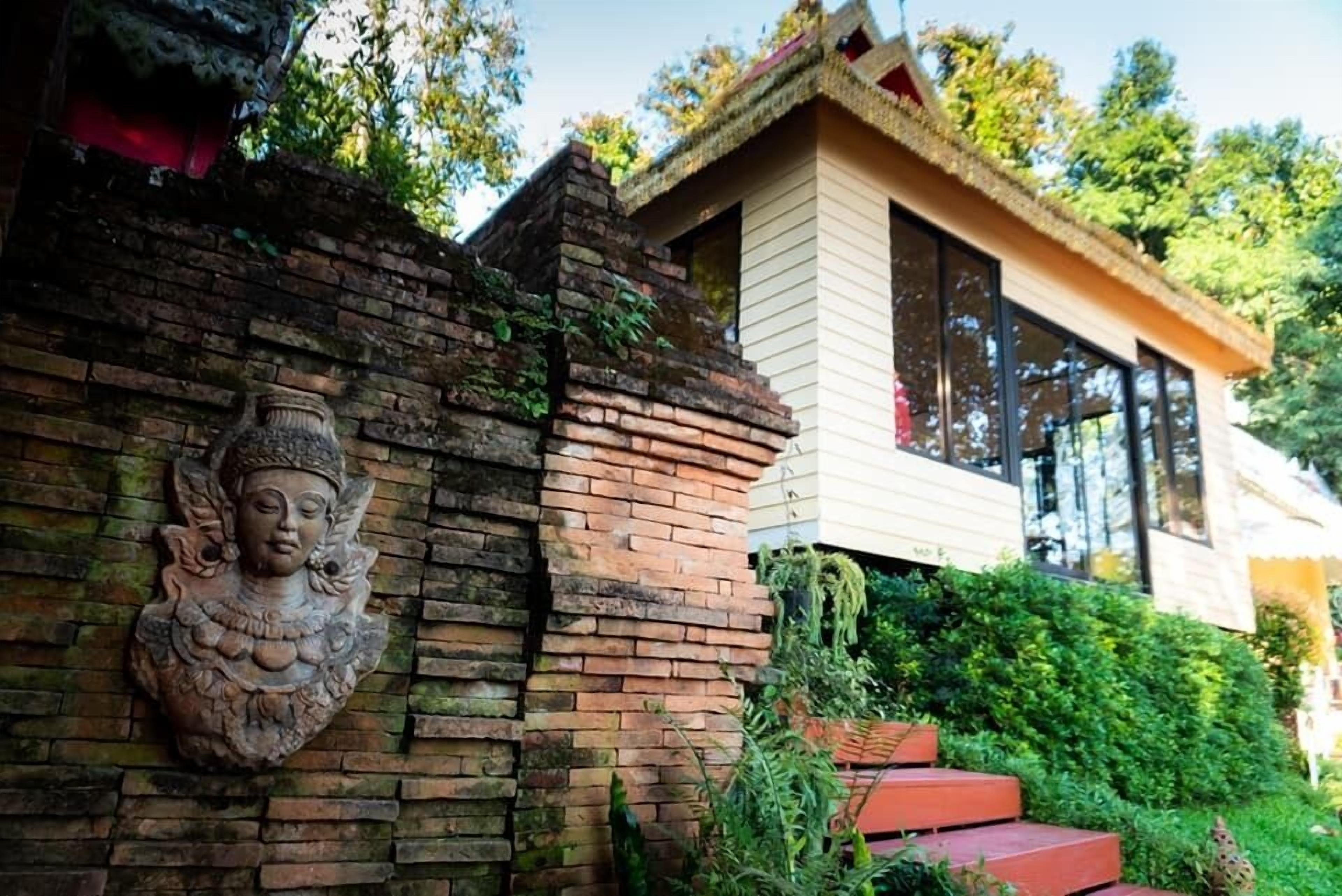 A traditional building with a brick wall and a Buddha statue.