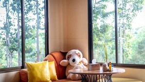 Ein gemütlicher Sitzbereich mit einer Couch, einem runden Tisch und Blick auf Grünflächen.