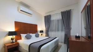 A hotel room with a large bed, two bedside tables with lamps, a wooden headboard, an air conditioning unit, a mirror, and a window with curtains. - Nova Park Hotel (Sharjah)