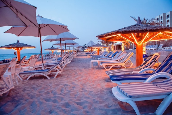 Am Strand, weißer Sandstrand, Liegestühle, Sonnenschirme