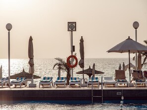 Am Strand, weißer Sandstrand, Liegestühle, Sonnenschirme