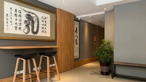 A modern interior with a wooden panel wall, two black bar stools, a potted plant, and a bench. - Yes Inn Taipei (Taipei)
