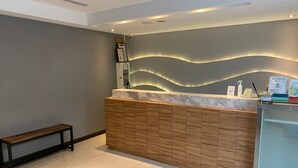 A reception desk with a marble top, wooden paneling, and a wavy light design on the wall. - Yes Inn Taipei (Taipei)