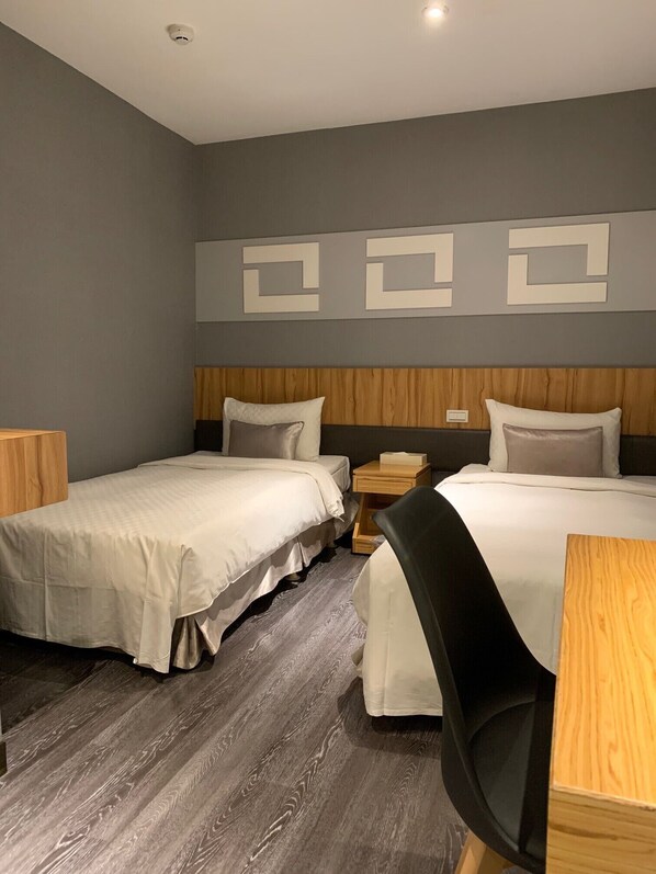 Two single beds with matching headboards and footboards, each with a pillow and nightstand, are set against a neutral gray backdrop.