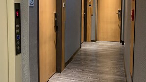 A hotel corridor with wooden doors, numbered 2 and 5, and a wheelchair accessibility sign. - Yes Inn Taipei (Taipei)