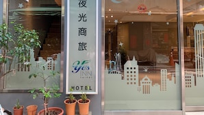 A hotel entrance with a sign reading "Yes Inn Taipei Hotel" and a cityscape design on the window. - Yes Inn Taipei (Taipei)