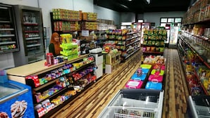 Un pasillo de un supermercado con diversos productos envasados en estantes y cestas.