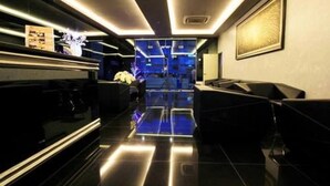 Un vestíbulo moderno con una recepción, zona de estar y vistas a un espacio amplio con techo iluminado en azul.