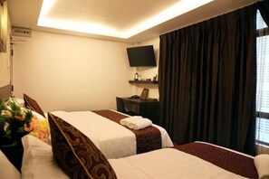 Habitación de hotel con dos camas, un televisor de pantalla plana, una mesita y un ventanal con cortinas.