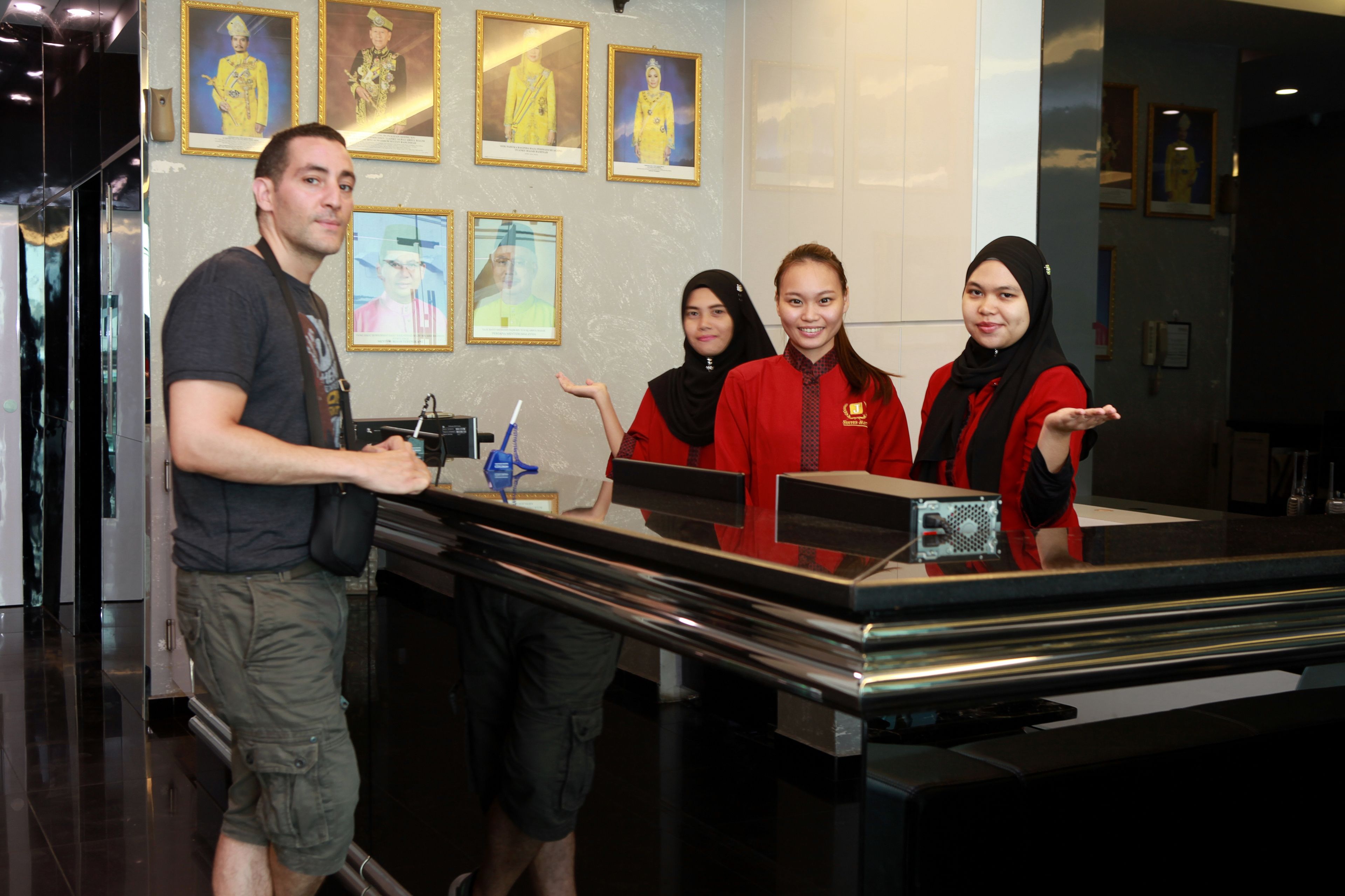 A reception desk with a man and two women in red uniforms.