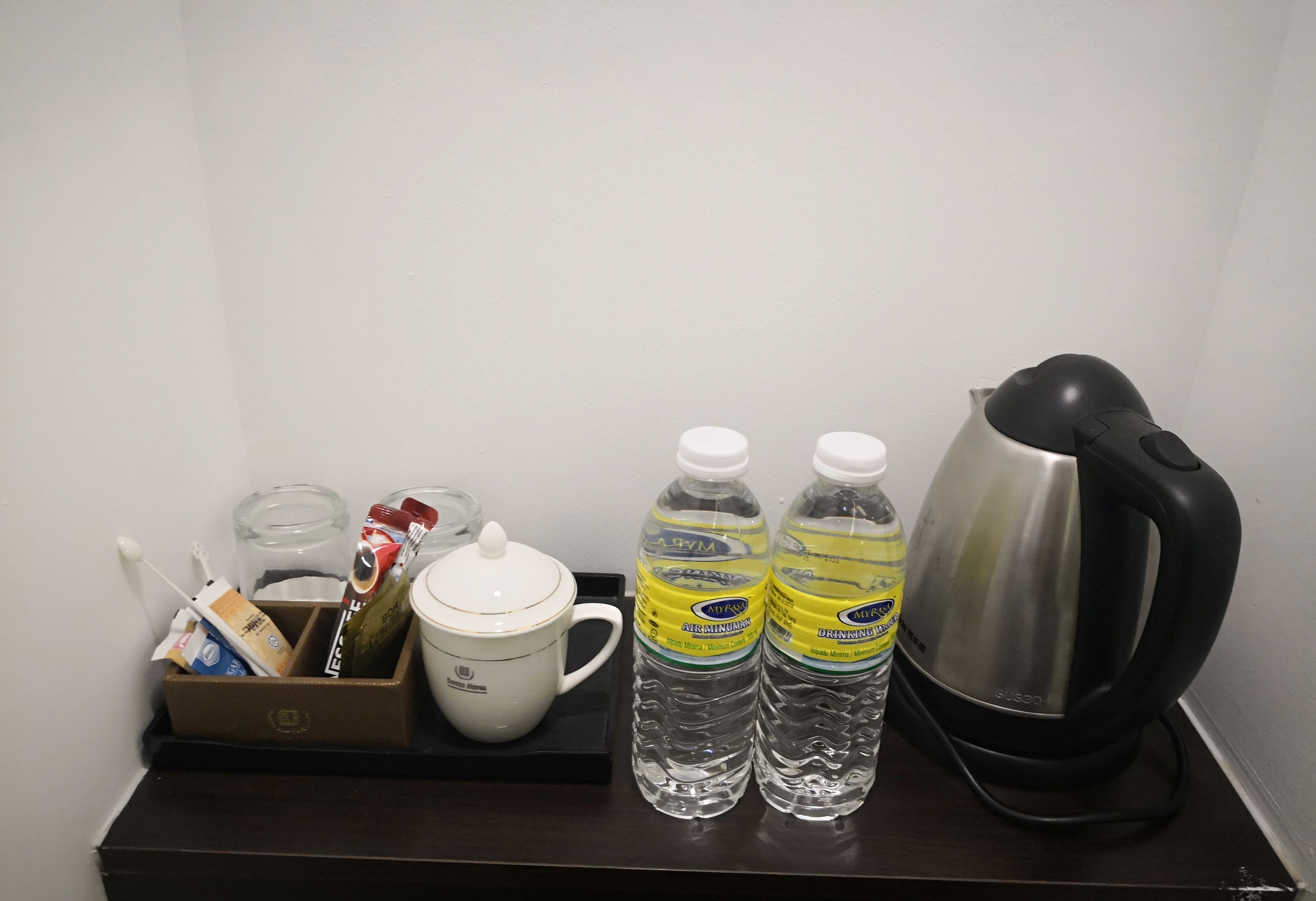 A small kitchenette area with a coffee maker, two bottles of water, a cup, and a box of tissues.