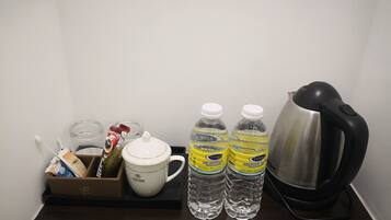 A small kitchenette area with a coffee maker, two bottles of water, a cup, and a box of tissues.