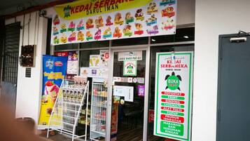 Un escaparate con un letrero que anuncia 'Kedai Serbaneka Darul Iman' y un menú de postres.
