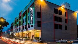 Un hotel con un llamativo letrero de neón, varios pisos y un diseño arquitectónico moderno.