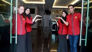 Un grupo de personas en un moderno vestíbulo de hotel con puertas de cristal y suelo reflectante.
