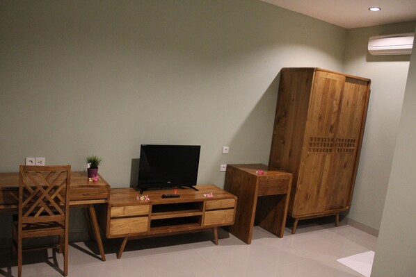 A room with a wooden desk, a television, a wardrobe, and a chair.
