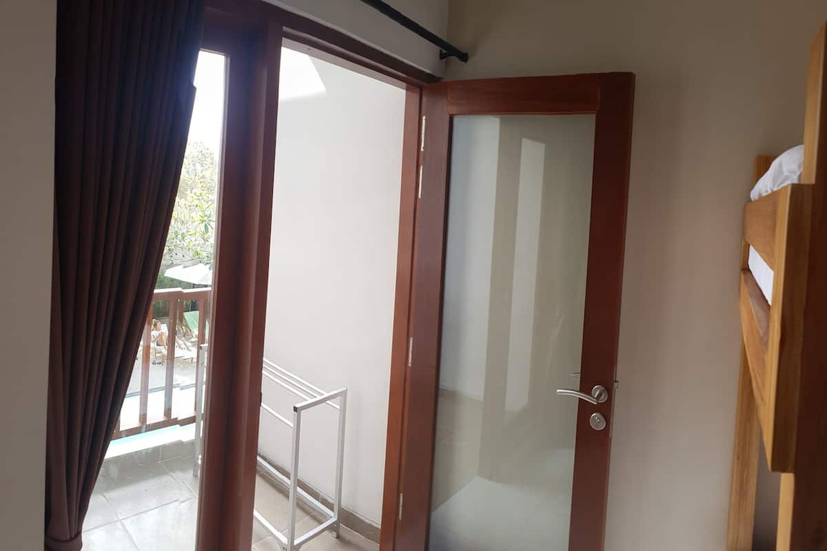 Quarto com beliche, cabeceira de madeira, porta para varanda e uma pequena escrivaninha com cadeira.