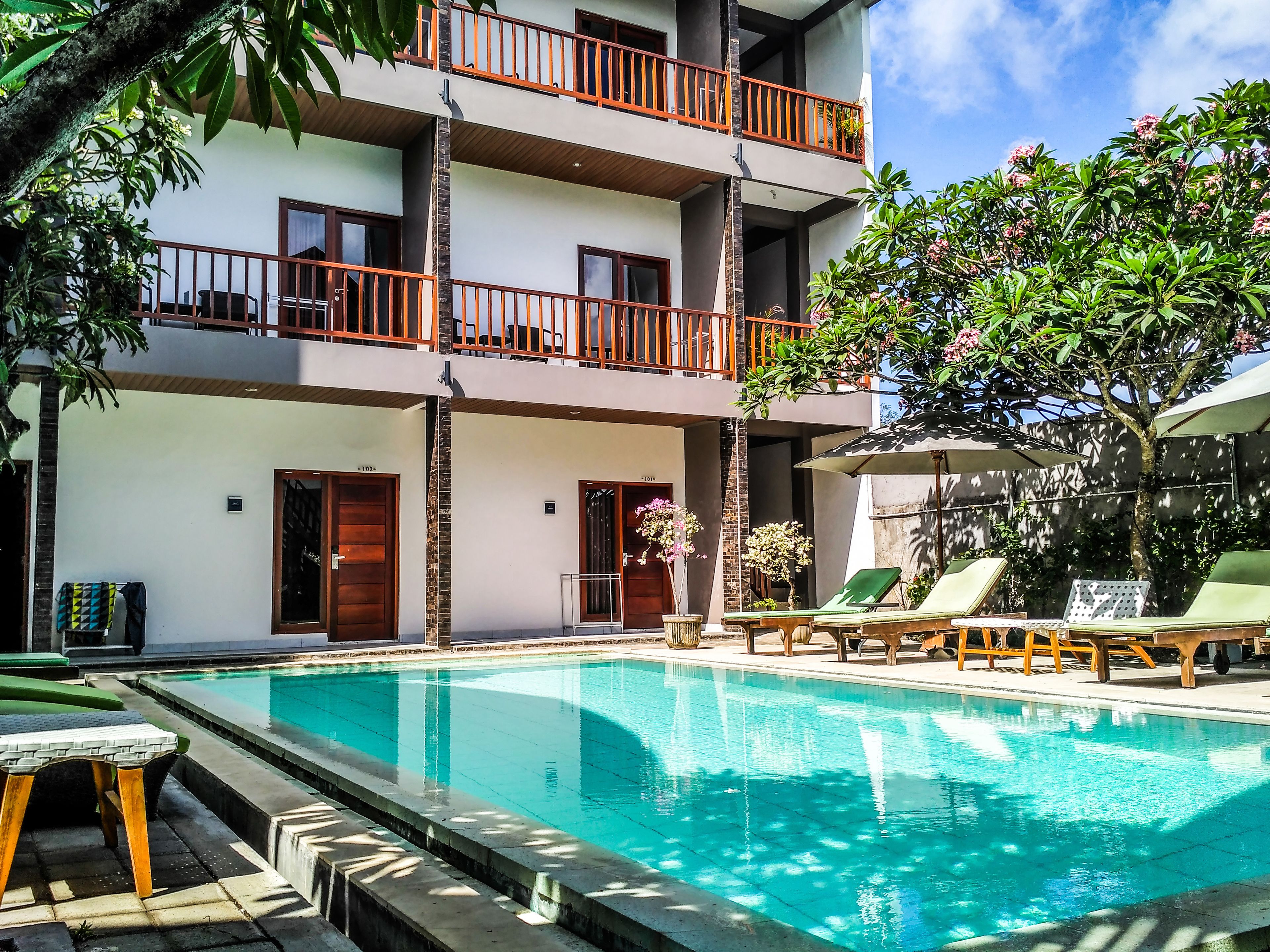 Un hôtel doté d’une piscine, de plusieurs balcons et d’un espace extérieur aménagé pour s’asseoir.