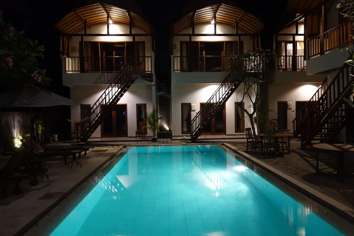 Um edifício de dois andares com piscina em frente.