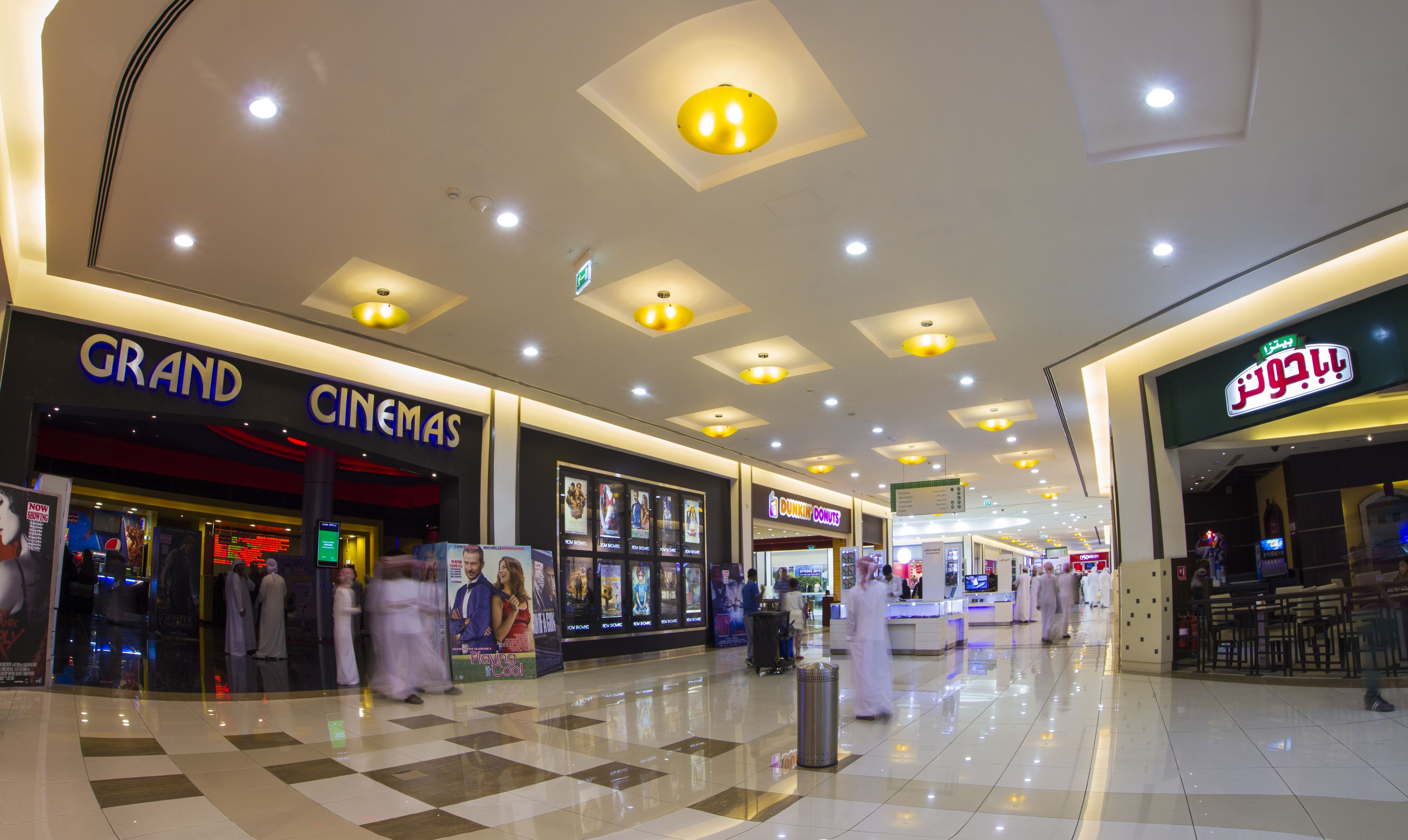 A shopping mall interior with a cinema, a bakery, and a clean tiled floor.