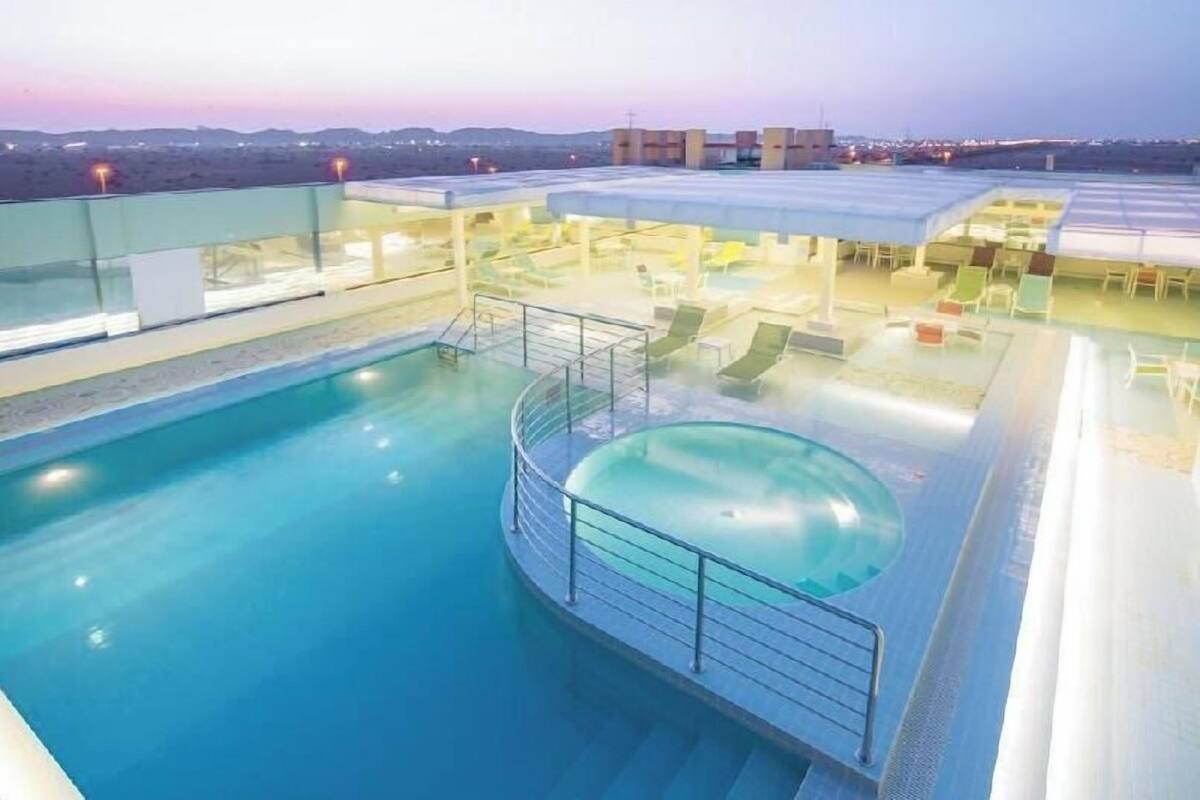 A rooftop swimming pool with lounge chairs and a sun terrace.